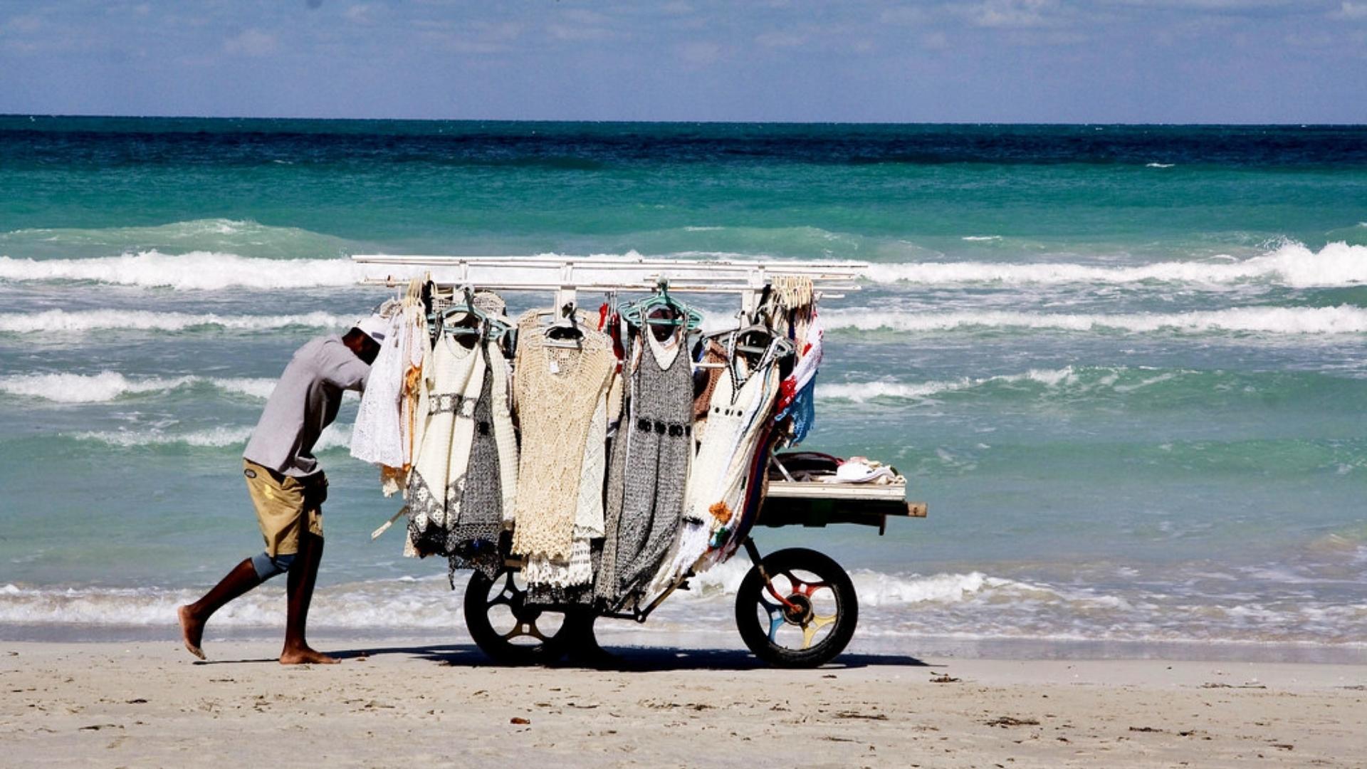 Un cubano arrastra una carretilla por arenas de Varadero, vendiendo vestidos
