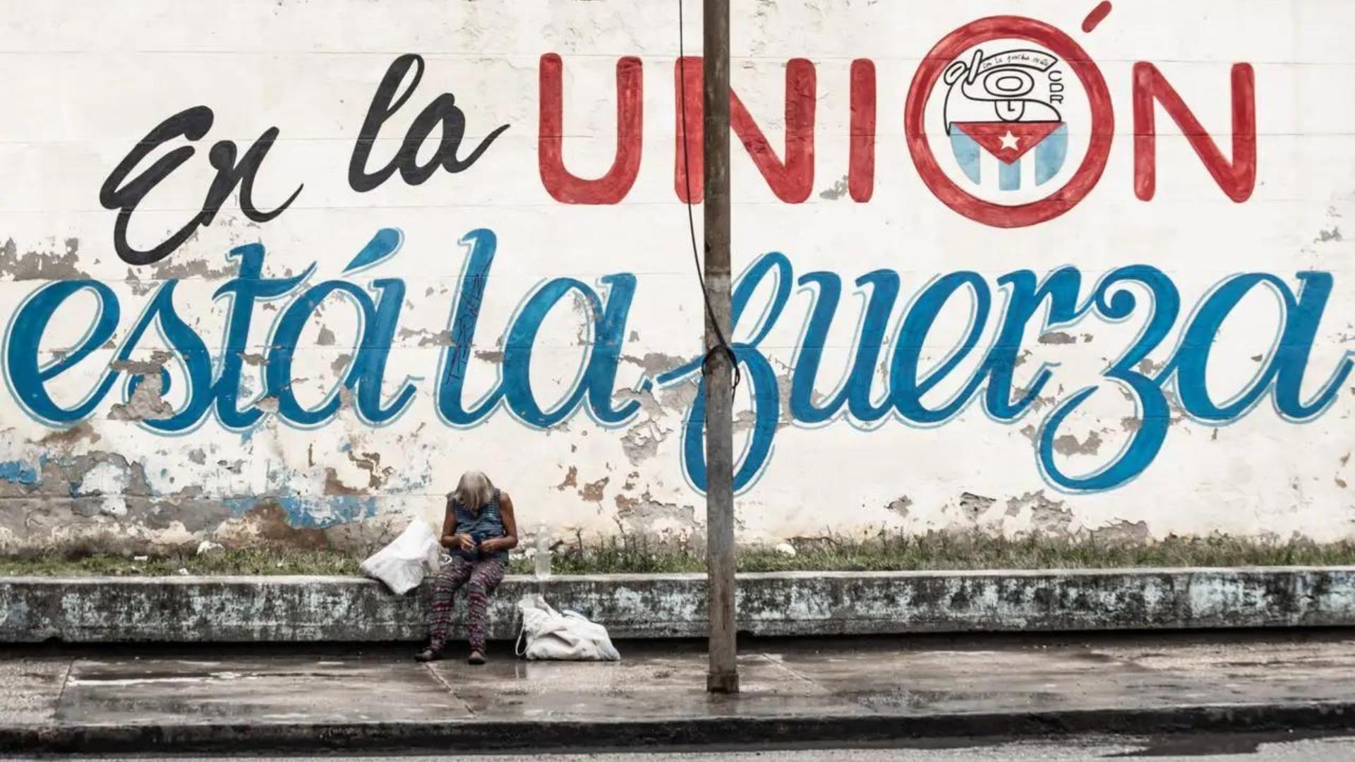 Anciana deambula cerca de cartel político en Cuba.