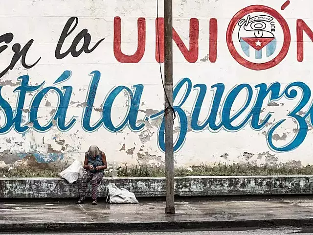 Anciana deambula cerca de cartel político en Cuba.