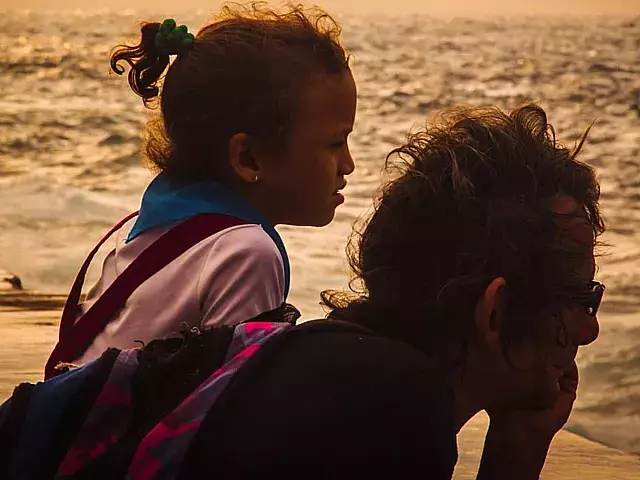 Niña con su padre mirando el mar.