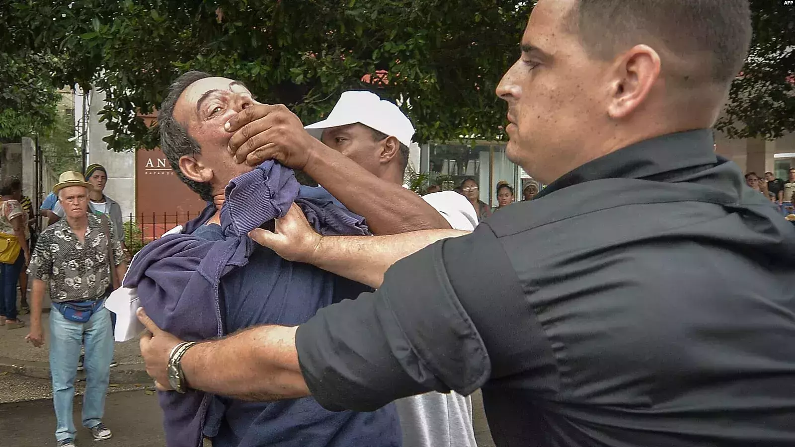 El periodista independiente Lázaro Yuri Valle sometido por agentes de la policía política en plena vía pública.