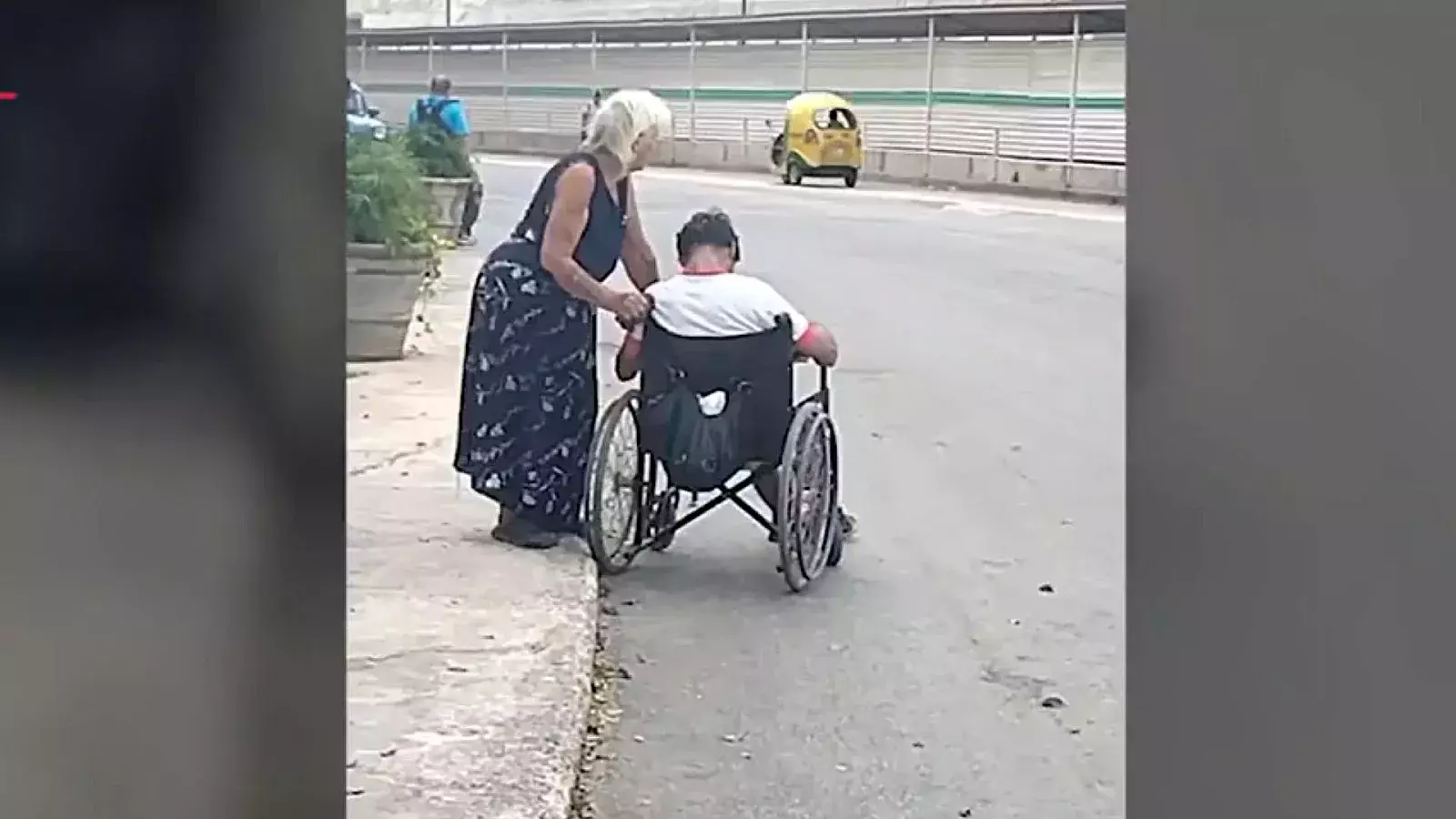 Anciana camina por las calles de La Habana junto a su nieto con discapacidad