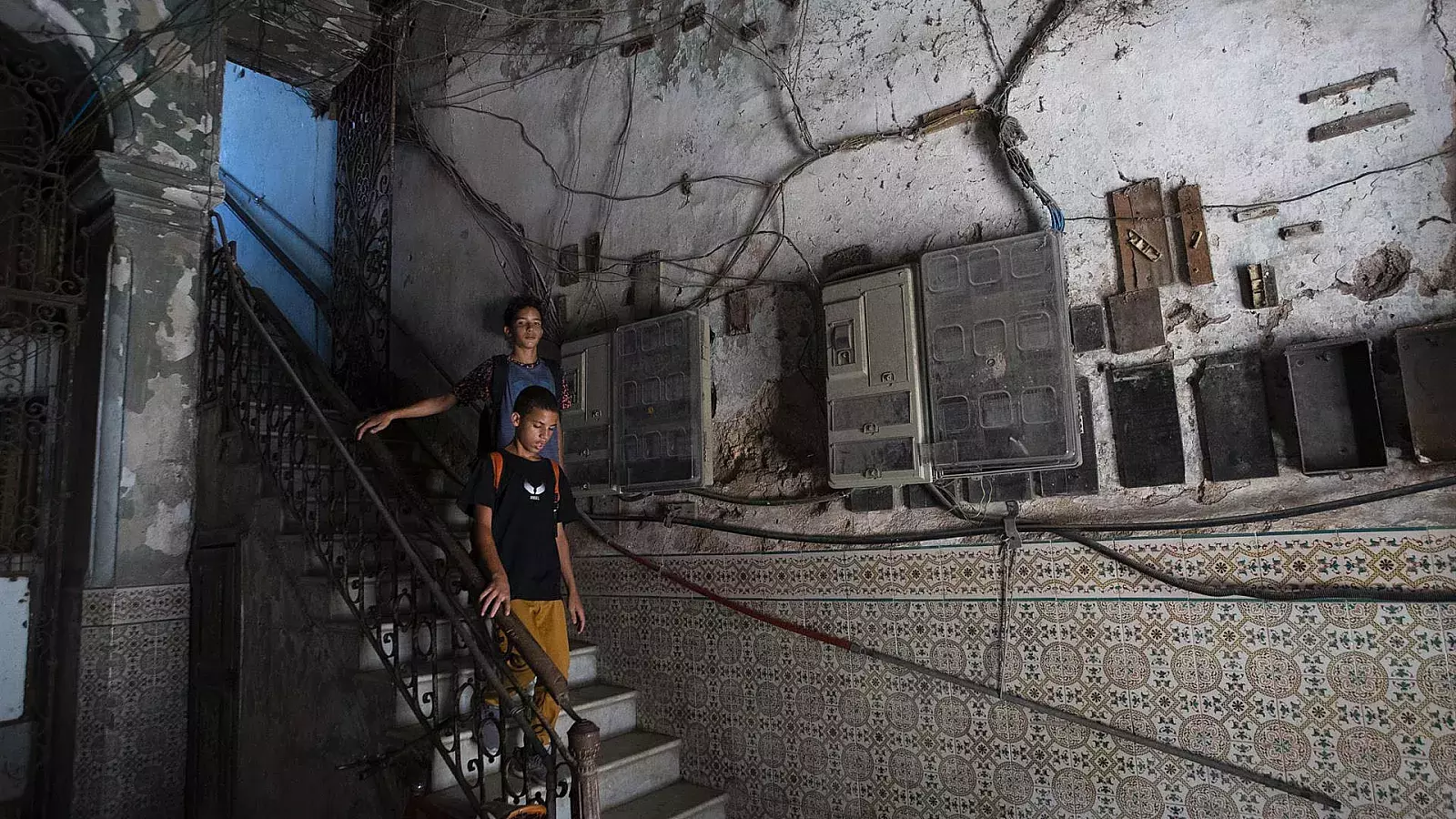 Dos personas pasan frente a varios contadores de corriente instalados en la pared de un edificio en La Habana