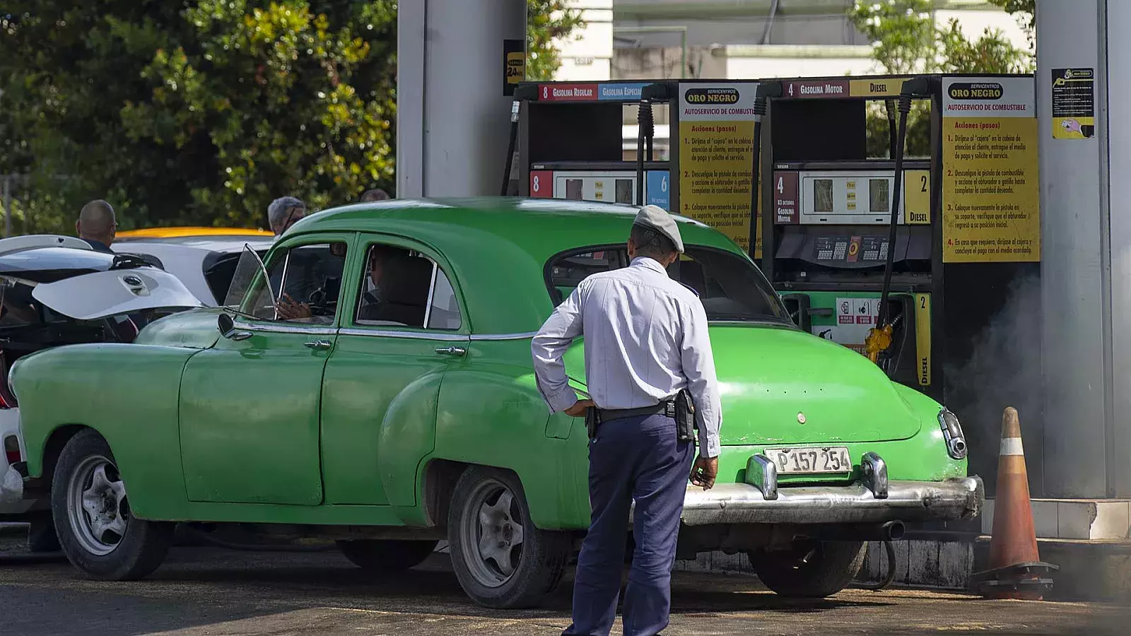 Un policía observa a un coche antiguo en una gasolinera en La Habana