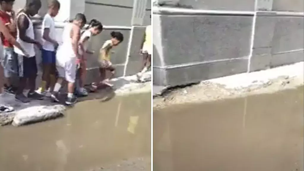 Niños intentan cruzar las aguas albañales cercanas a su escuela