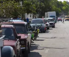 Varias personas esperan en sus carros a que abastezcan de combustible una gasolinera, en La Habana