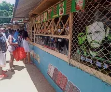 Varias personas compran en un mercado frente a una imagen de Fidel Castro