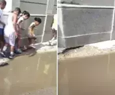 Niños intentan cruzar las aguas albañales cercanas a su escuela