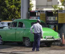 Un policía observa a un coche antiguo en una gasolinera en La Habana